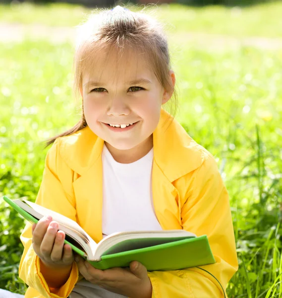 Klein meisje is het lezen van een boek buitenshuis — Stockfoto