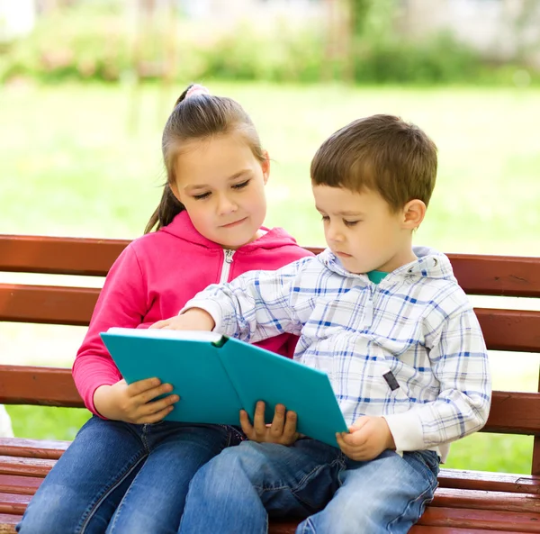 Malý chlapec a dívka čte knihu — Stock fotografie
