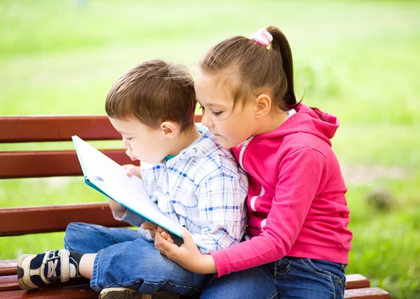 El niño y la niña están leyendo el libro — Foto de Stock