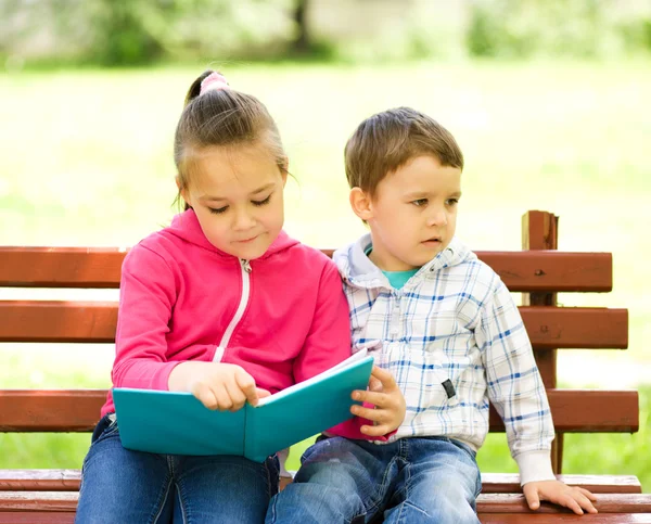 El niño y la niña están leyendo el libro Imagen de stock