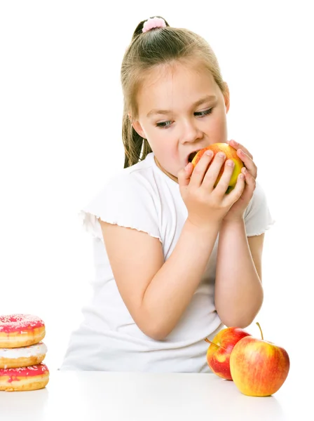 Linda chica elegir entre manzanas y pastel — Foto de Stock