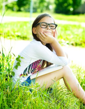 küçük kız açık havada bir kitap okuma