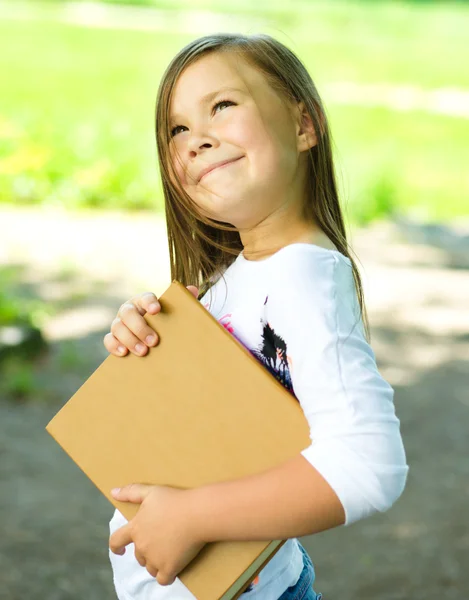 Liten flicka läser en bok utomhus — Stockfoto