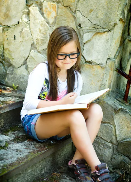 Little girl is reading a book outdoors — Stock Photo, Image