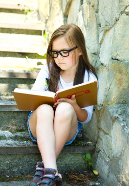 küçük kız açık havada bir kitap okuma