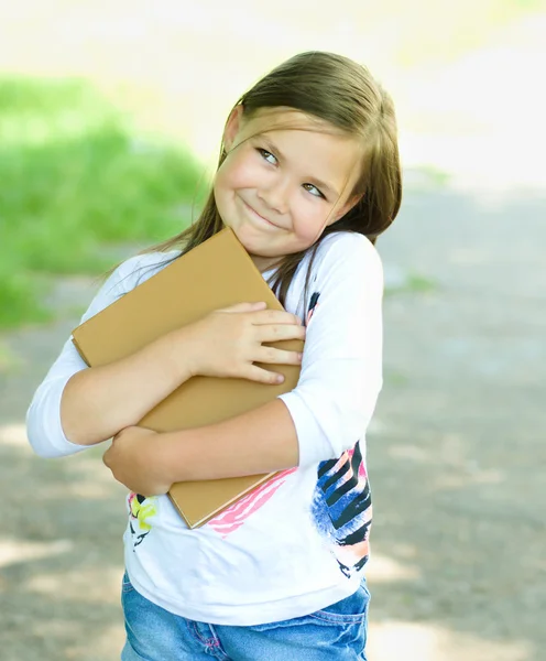 Liten flicka läser en bok utomhus — Stockfoto