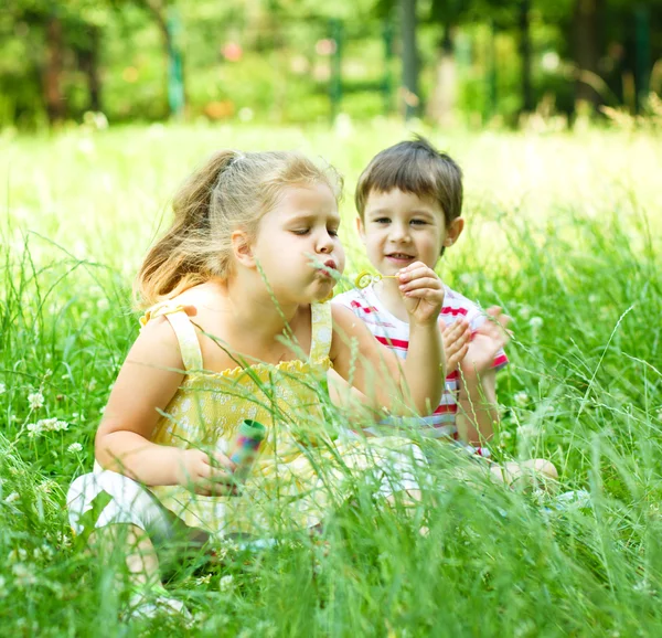 Girl and boy blowing soap bubbles — Stock Photo, Image