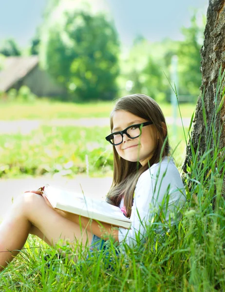 Little girl is reading a book outdoors — Stock Photo, Image