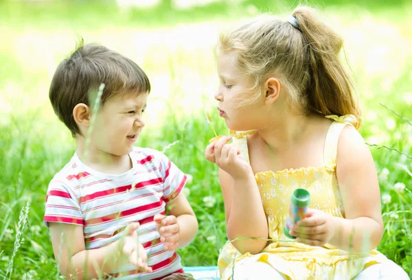 Girl and boy blowing soap bubbles — Stock Photo, Image