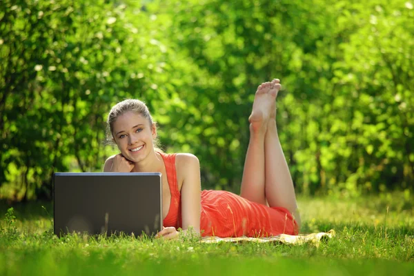 Jovem com laptop na grama verde no parque — Fotografia de Stock