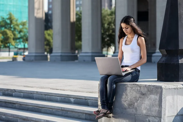 Молода жінка з ноутбуком, що сидить на сходах, біля невідомого — стокове фото