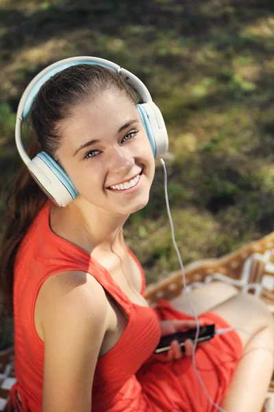 Młoda kobieta z słuchawkami na zielonej trawie w parku — Zdjęcie stockowe