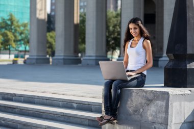 Merdivenlerden univ yakın oturan bir dizüstü bilgisayar ile genç bir kadın
