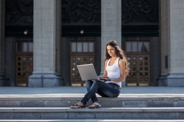 Merdivenlerden univ yakın oturan bir dizüstü bilgisayar ile genç bir kadın