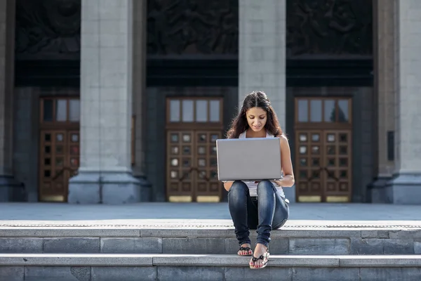 Merdivenlerden univ yakın oturan bir dizüstü bilgisayar ile genç bir kadın