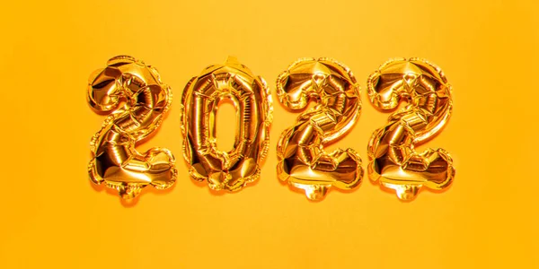 Bonne année 2022 célébration. Figures de ballons en or brillant, ballons Nouvel An avec des étoiles scintillantes sur fond jaune vif. Noël et Nouvel An. Ballons feuille d'or 2022 carte cadeau — Photo