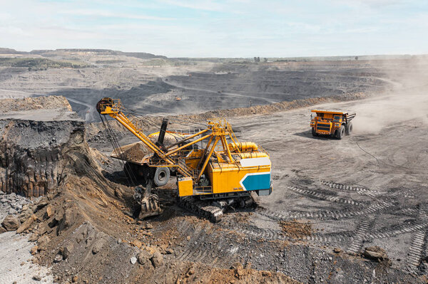 Panoramic aerial view of coal mine. Open pit mine industry, big yellow mining truck for coal quarry. Open coal mining anthracite mining. Pit on coal mining by open way. Rock loading in trucks