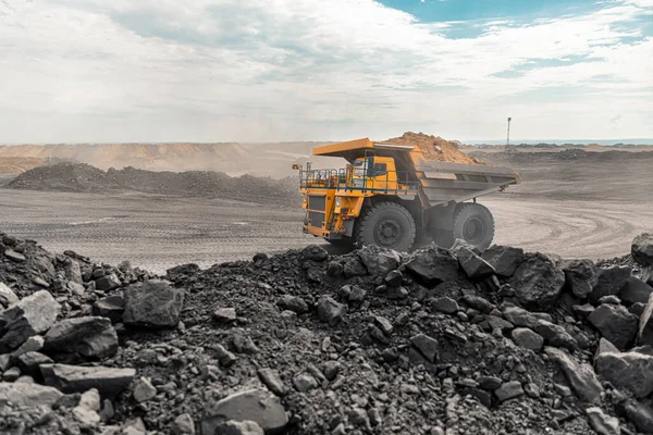 Large quarry dump truck. Big yellow mining truck at work site. Loading coal into body truck. Production useful minerals. Mining truck mining machinery to transport coal from open-pit production — Stock Photo, Image