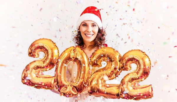 Nouvel An 2022 nombre d'or ballons. Belle femme avec des ballons Célébration du Nouvel An Eve Party. En bonnet rouge du Nouvel An. Fille souriante en robe brillante brillante à la célébration. Concepts mode de vie des jeunes — Photo
