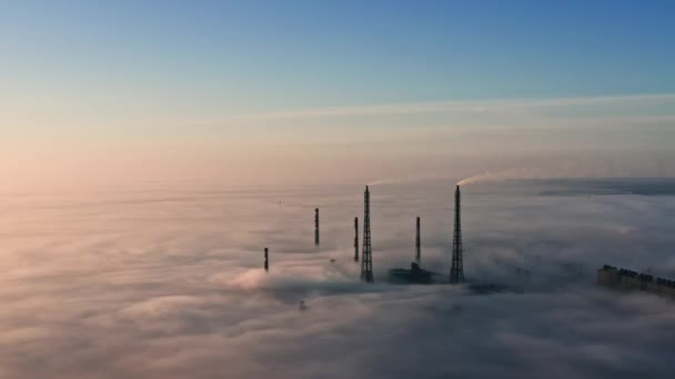 Vista aérea de fábrica en niebla. Volar en la niebla, volar en la niebla. Cámara aérea grabada encima de la planta. Vuelo por encima de las nubes hacia el sol. Clima brumoso, vista desde arriba. Punto de vista de las aves — Vídeos de Stock