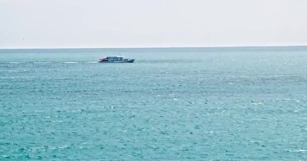 Mar azul turquesa con olas. Vista en día soleado al océano. La superficie del agua retrocediendo en la distancia, olas en el mar, barco está navegando a lo largo del mar. Olas de agua azul superficie hermoso fondo — Vídeo de stock