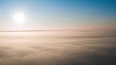 Hava görüntüsü. Sisin içinde uçmak, sisin içinde uçmak. Hava kamerası görüntüsü. Bulutların üzerinden güneşe doğru uç. Sisli hava, yukarıdan manzara.