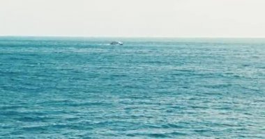 Dalgalı mavi turkuaz deniz. Güneşli bir günde okyanusu seyret. Su yüzeyi uzaklığa çekiliyor, dalgalar denizde, gemi deniz boyunca ilerliyor. Mavi su dalgaları yüzey güzel arka plan