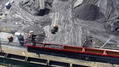 Yukarıya bakın, yükleyici vagonlara kömür yüklüyor. Hava manzaralı Uhd 4k yük treni vagonları ve kömürlü ayakta duran tren.