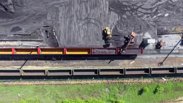 Вид сверху, погрузчик загружает уголь в вагоны. Вид с воздуха UHD 4K грузового поезда с вагонами и стоячий поезд с углем — стоковое видео