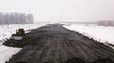 Yol manzarası kışın çalışır. Kışın kırsalda yol yapımı için ağır inşaat ekipmanları var. Kış yolu üzerindeki manzarayı göster