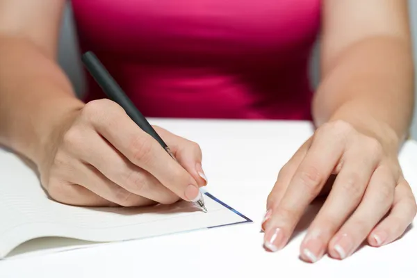 Las manos de la mujer sosteniendo una pluma escribiendo un texto — Foto de Stock