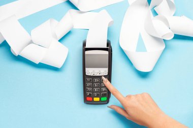 Mavi arka planda uzun kasiyer bandı olan pos terminal. Kadın eli bir posizyon düğmesine basar. alışveriş teması