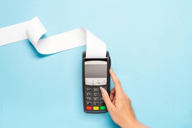 Mavi arka planda uzun kasiyer bandı olan pos terminal. Kadın eli bir posizyon düğmesine basar. alışveriş teması