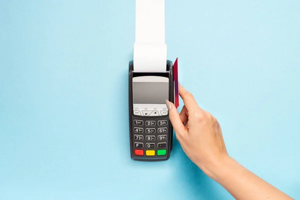 青い背景に長いレジテープ付きのPos端末 女性の手はクレジットカードで支払う 買い物のテーマ ロイヤリティフリーのストック写真