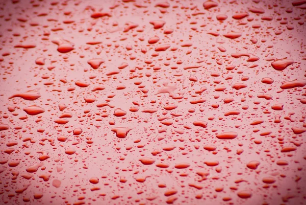 Яскраві апельсинові та червоні краплі води на капоті автомобіля — стокове фото