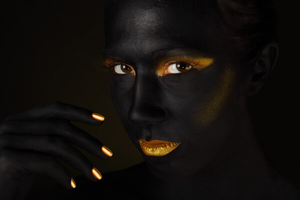 Beautiful dark face isolated on black with orange make up