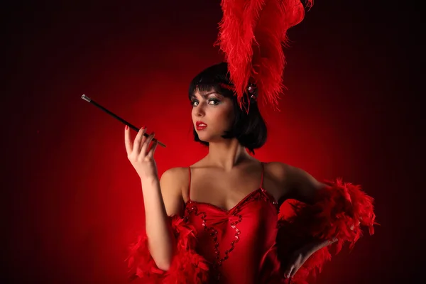 Danseuse burlesque avec plumage rouge et robe courte, fond noir — Photo