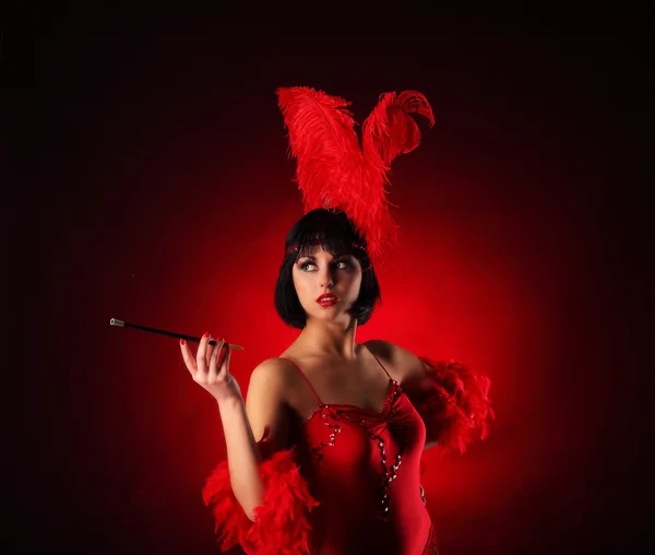 Danseuse burlesque avec plumage rouge et robe courte, fond noir — Photo