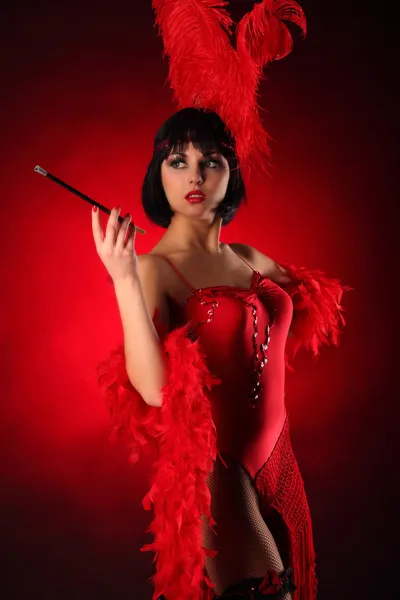 Danseuse burlesque avec plumage rouge et robe courte, fond noir — Photo