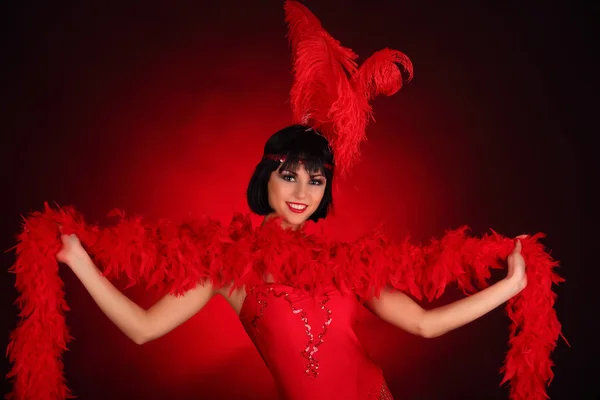 Dançarina burlesca com plumagem vermelha e vestido curto, fundo preto — Fotografia de Stock