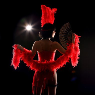 Kırmızı kuş tüyü ve kısa elbise, siyah arka plan ile burlesque dansçı