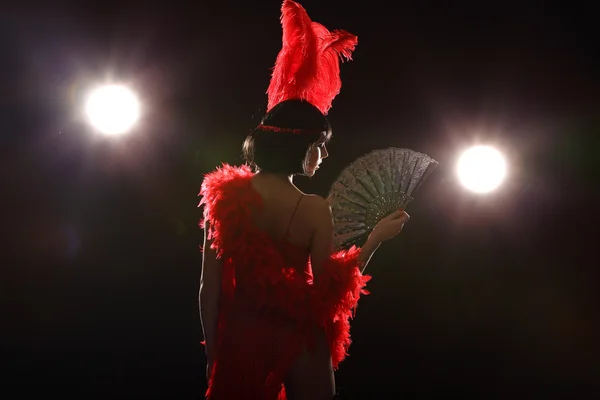 Танцовщица бурлеска с красным оперением и коротким платьем, черный фон — стоковое фото