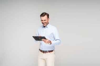 Tablet bilgisayar kullanan neşeli sakallı adam. Mutlu yakışıklı iş adamı çalışıyor. Bir sürü kopya alanı var. Stüdyo çekimi