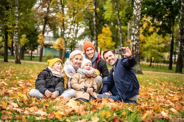 真正的人的生活方式和家庭情感的概念 快乐的爸爸妈妈和儿子一起玩乐 在秋天的公园用手机自拍 — 图库照片