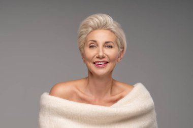 Sarışın, beyaz, orta yaşlı, kısa saçlı bir kadın. Zarif makyajlı çekici bir bayan ve sıcak bir süveter giyen, stüdyoda poz veren bir gülümseme. Bir sürü kopyalama alanı