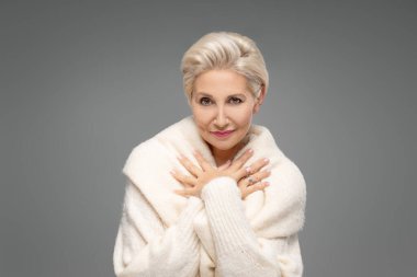 Sarışın, beyaz, orta yaşlı, kısa saçlı bir kadın. Zarif makyajlı çekici bir bayan ve sıcak bir süveter giyen, stüdyoda poz veren bir gülümseme. Bir sürü kopyalama alanı