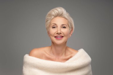 Sarışın, beyaz, orta yaşlı, kısa saçlı bir kadın. Zarif makyajlı çekici bir bayan ve sıcak bir süveter giyen, stüdyoda poz veren bir gülümseme. Bir sürü kopyalama alanı