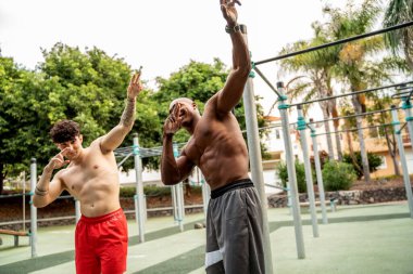 Açık hava jimnastiğinden sonra gülümseyen iki genç arkadaş. Endorfin. Egzersiz yaptıktan sonra kaslı çocuklar. Açık spor salonu. Hobi olarak. Sağlıklı yaşam tarzı.