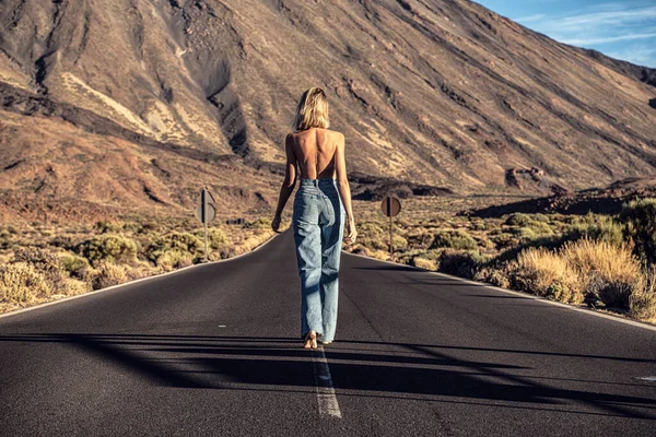 ジーンズで女性のトップレス旅行者離れて野生の山の風景の上に通りを歩いてください バックビュー 欲望旅行の概念 観光客だ フェミニスト — ストック写真
