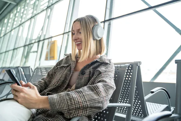 Mulher Branca Sorrindo Usando Smartphone Fones Ouvido Terminal Aeroporto Sentado — Fotografia de Stock